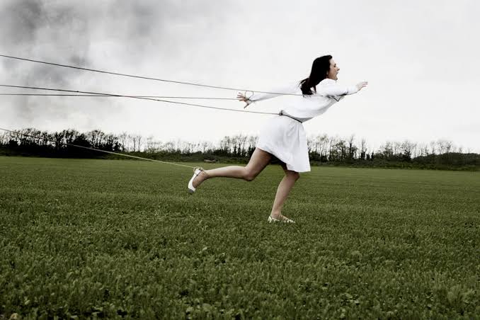 Woman being held back by strings